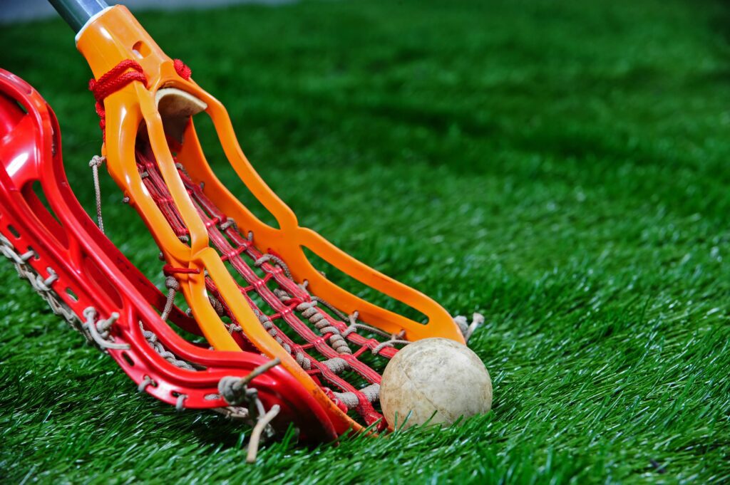 Lacrosse sticks fighting for lacrosse ball on ground.